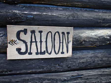 Wild west American saloon sign hanged on a wooden house