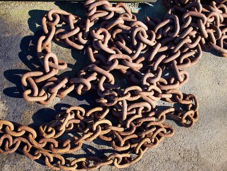 Old rusty metal iron chain on the ground in a port