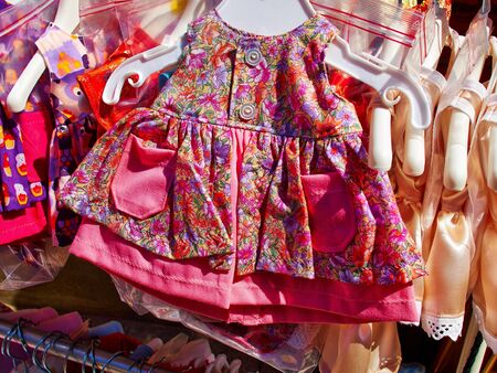Baby girl beautiful elegant bright summer dresses on hangers in a display shopの写真素材