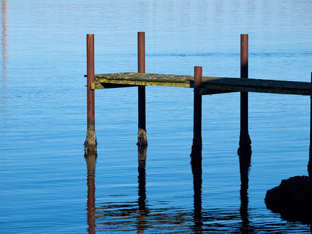 Small rural wooden bridge dock pier over crystal clear water