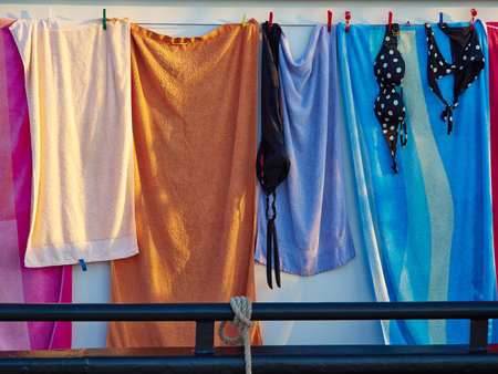 Towels and bathing swim suits drying on the clothesline on a sail boat summer background imageの写真素材