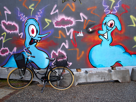 Urban city scene classical retro style black bicycle bike in front of a Graffiti wallのeditorial素材