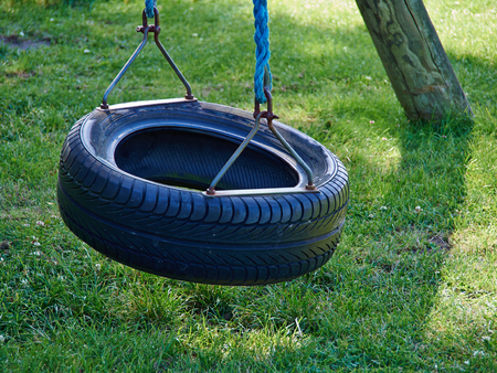 Tire swing hanging in a payground with green grass lawn backgroundの写真素材