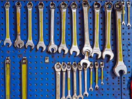 Selection of spanners wrenches tools hanged in a workshop garage factory industrial background image