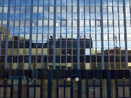 Corporate modern office building with glass windows and reflection of sky