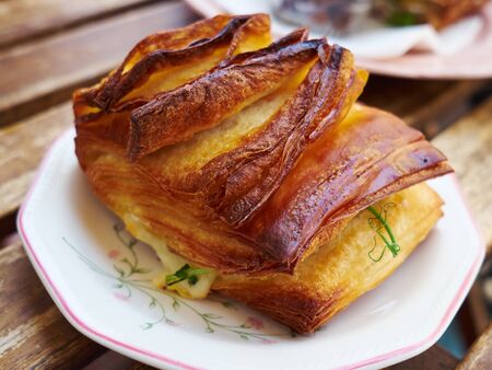 Freshly baked puff pastry filled with cheese on a nice plate in a coffee shopの写真素材