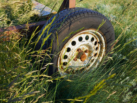 Closeup of an Old rusty car wheel mount in a green field - grunge retro background image