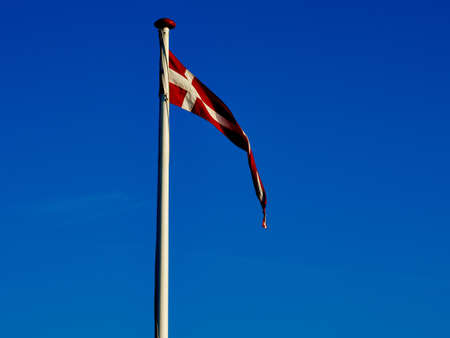 Flag of Denmark up high in the air with clear blue sky background      