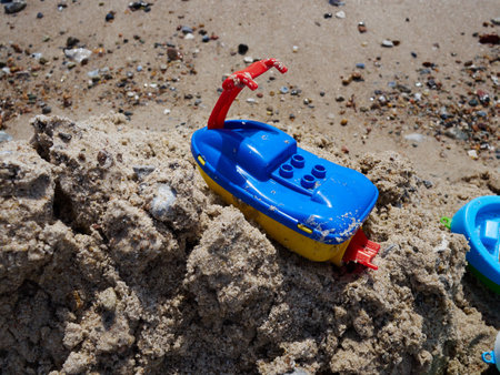 Colorful plastic toy floating boats on the sand beach by the ocean sea ready for fun play timeの写真素材