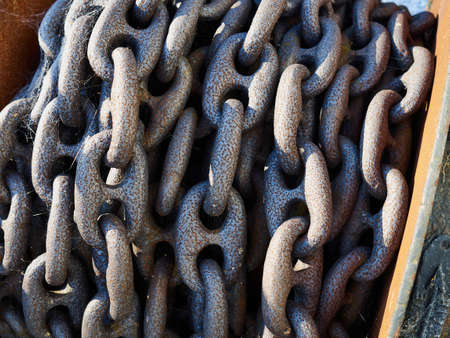 Heavy anchor iron metal chains in a pile by the portの写真素材