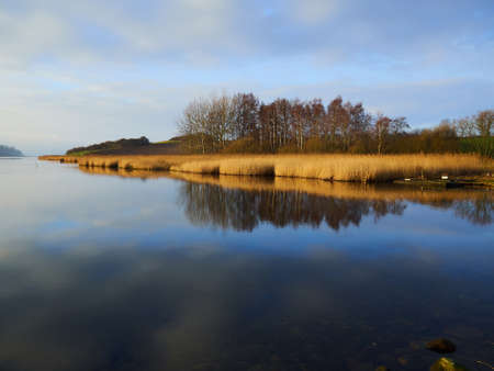 Magical tranuil beautiful with clear calm water sunset with great clouds formation by the sea shore Funen Denmarkの写真素材