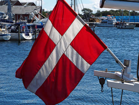 Flag of Denmark up high on a sail yacht in a small marinaの写真素材