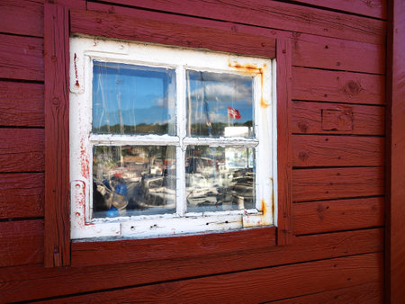 Old wooden window with reflection of a red wood house and space for graphics and text