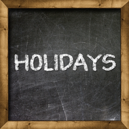 Holidays handwritten with white chalk on a blackboard の写真素材