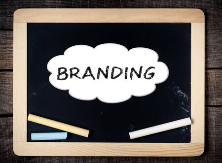 Branding handwritten with white chalk on a blackboard on wood background の写真素材