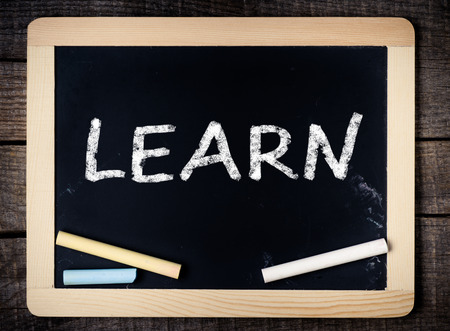 Learn handwritten with white chalk on a blackboard on wooden background の写真素材