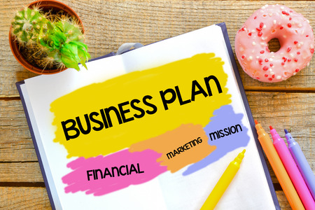 Business plan written in the notebook on a wooden backgroundの写真素材