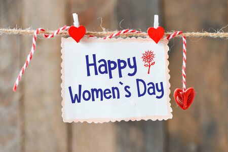 Happy Women's Day on paper , hanging on a rope with red heartsの写真素材