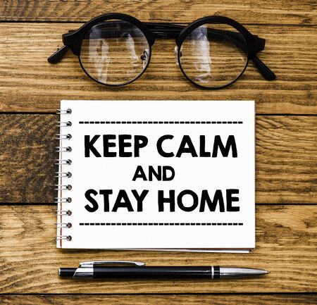 Keep calm and stay home text on note with pen