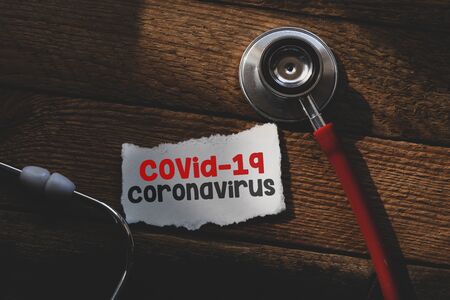 COVID-19 text on white sheet of paper, stethoscope. Covid-19 or Coronavirus Concept.の写真素材