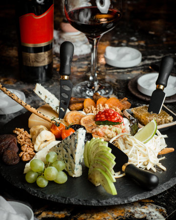 Many different varieties of cheese, dried fruits, fruits, nuts and honey with a smoke effect on the tableの写真素材