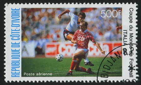 IVORY COAST - CIRCA 1990: stamp printed by Ivory Coast, shows Soccer players and ball, circa 1990.のeditorial素材