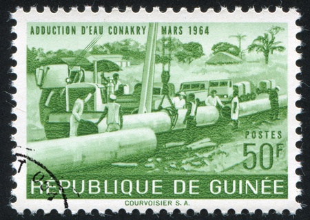 GUINEA CIRCA 1964: stamp printed by Guinea, shows Laying pipe, circa 1964の写真素材
