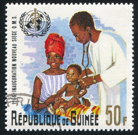 GUINEA CIRCA 1967: stamp printed by Guinea, shows Physician examining Infant, circa 1967のeditorial素材