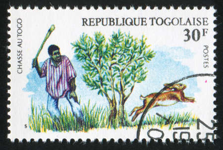 TOGO - CIRCA 1975: stamp printed by Togo, shows Rabbit Hunter with Club, circa 1975の写真素材