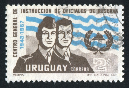 URUGUAY - CIRCA 1969: stamp printed by Uruguay, shows Training Center Emblem and Officer in Uniform and as Civilian, circa 1969のeditorial素材