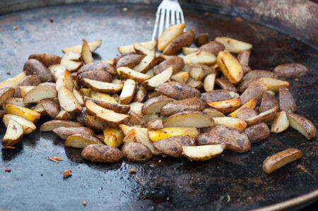 Delicious fried potatoes on the fire in a large pan.の写真素材