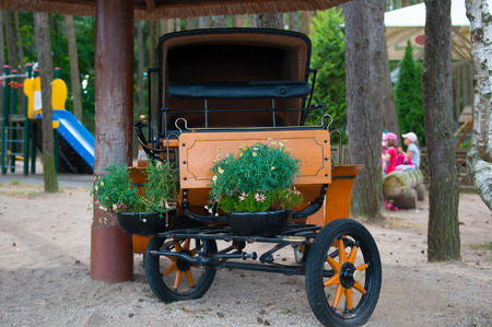 Ancient coach and flower beds on the playground. Garden.の写真素材