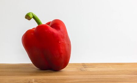 Red sweet pepper on wooden cutting board and white background.の写真素材