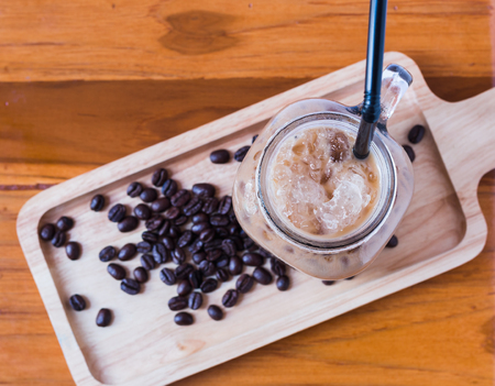 Glass of iced coffee and coffee beans on wooden tray with top view.の写真素材