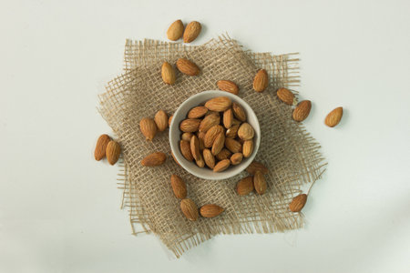 Full cup of almonds nut on sackcloth isolated on white background.の写真素材