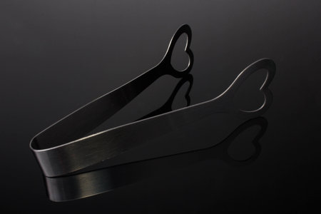 Stainless steel love heart ice tongs isolated on gray gradient backgroundの写真素材