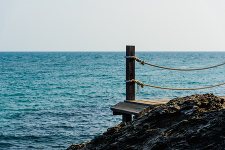 The wood walkway on the rock with sea backgroundの写真素材