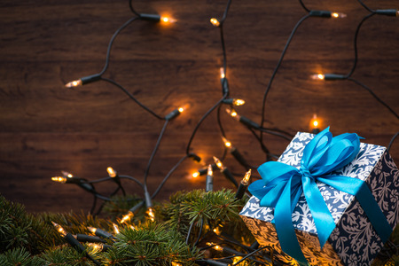 Christmas gift box with blue bow and bokeh lights on a fir-tree branchの写真素材