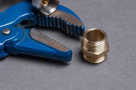 Adjustable spanner, nipple, and  braided stainless steel water hose over grey backgroundの写真素材