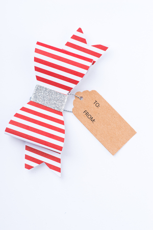 Red gift bow with stripes and cardboard tag over the white backgroundの写真素材