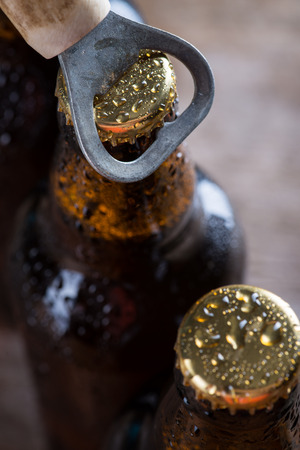 Brown ice cold beer bottles with water drops and old openerの写真素材