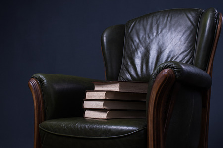 Cosy green leather armchair with books in front of the wallの写真素材