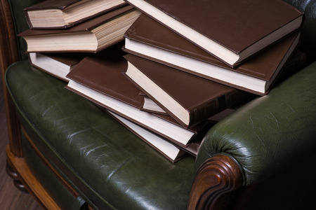 Cosy green leather armchair with books in front of the wallの写真素材