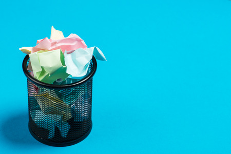 Colorful paper in a garbage bin on a blue surfaceの写真素材