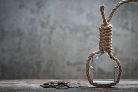 Hangman's noose with house and coins on brown wooden surfaceの写真素材