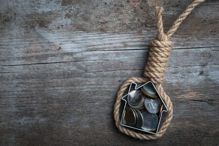 Hangman's noose with house and coins on brown wooden surfaceの写真素材