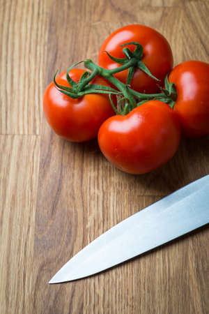 Fresh and tasty farm tomatoes with knife on a wooden table