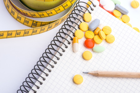 Fresh green apple with measuring tape, notebook and pills on white tableの写真素材