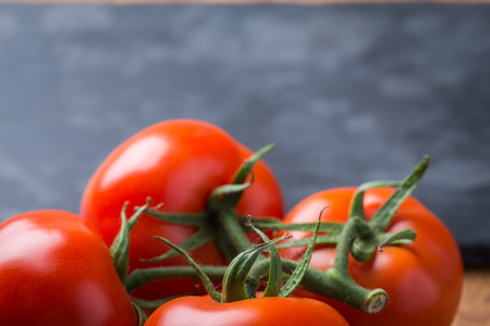 Fresh and tasty red tomatoes on a black stone serving boardの写真素材