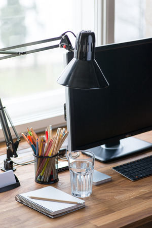 Light and cozy workplace with color pencils and glass of waterの写真素材